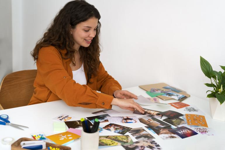 Mujer seleccionando fotografías para plasmar una de las ideas creativas para envolver regalos.