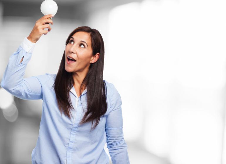 mujer sosteniendo un bombillo haciendo alusión al ahorro de energía en el hogar
