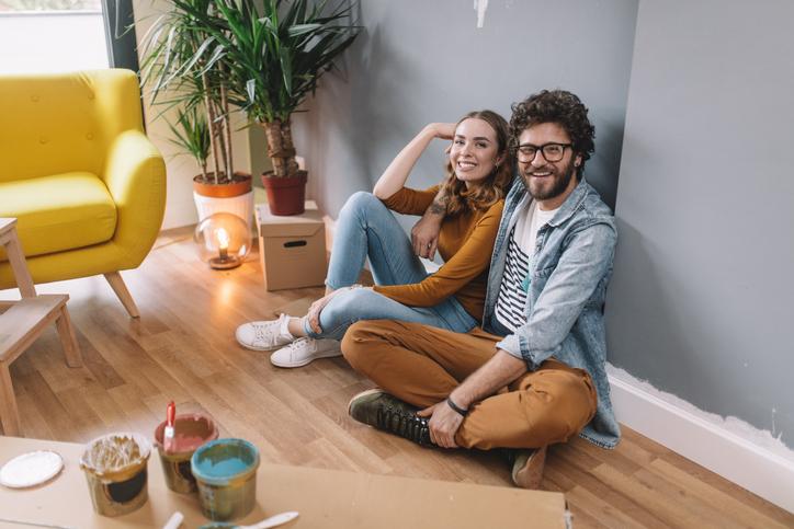 Pareja sentada en el suelo aprendiendo a decorar un apartamento pequeño.