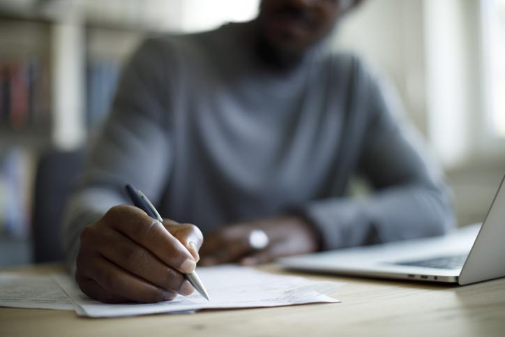 Hombre moreno tomando notas en un papel, imagen de referencia sobre vivir en Bogotá y sus oportunidades de estudio.