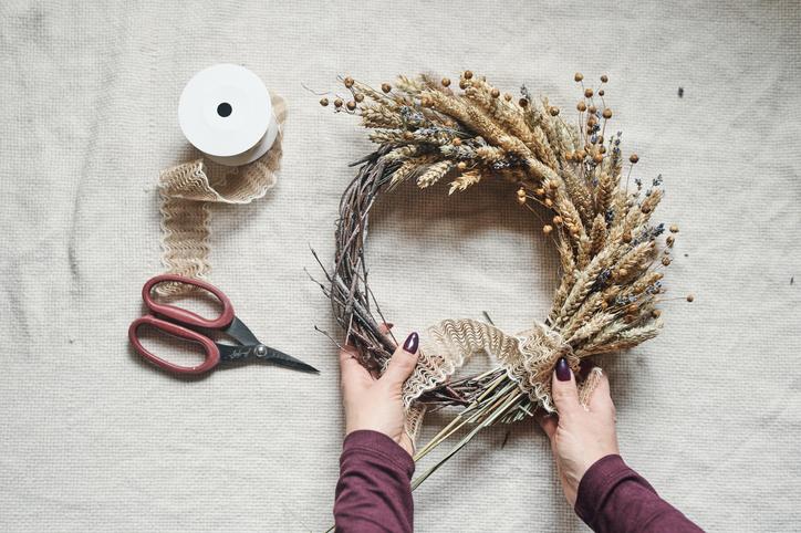Manos de mujer creando una corona navideña para la puerta siguiendo las tendencias de decoración navideña.