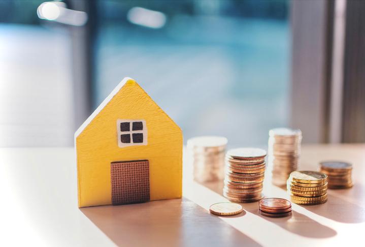 Casa a pequeña escala con monedas para hacer referencia a invertir la prima de Navidad para comprar vivienda.