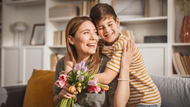 niño entregando carta que hizo con ideas para celebrar el Día de la Madre en casa