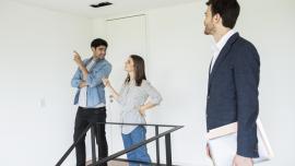 Agente inmobiliario ayudando a buscar la casa en arriendo ideal a una joven pareja.