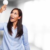 mujer sosteniendo un bombillo haciendo alusión al ahorro de energía en el hogar
