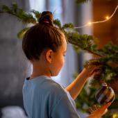 Niña poniendo una bola al árbol de Navidad siguiendo las tendencias de decoración navideña.