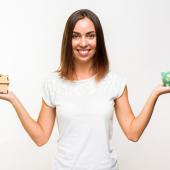 mujer levantando alcancía representando cómo organizar las finanzas para comprar casa en 2025