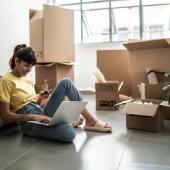 Imagen de referencia para multifamily en Bogotá, una mujer joven sentada en la sala de su nuevo apartaestudio mientras desempaca.
